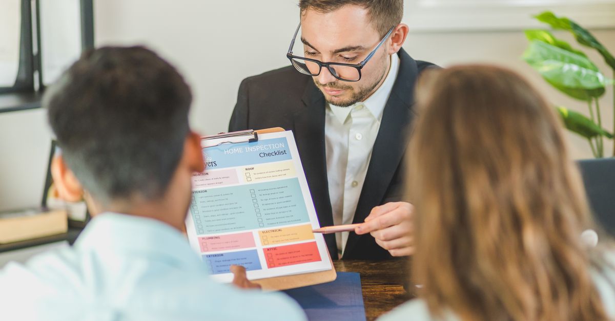 Real estate agent explaining home inspection checklist to clients in an office setting.